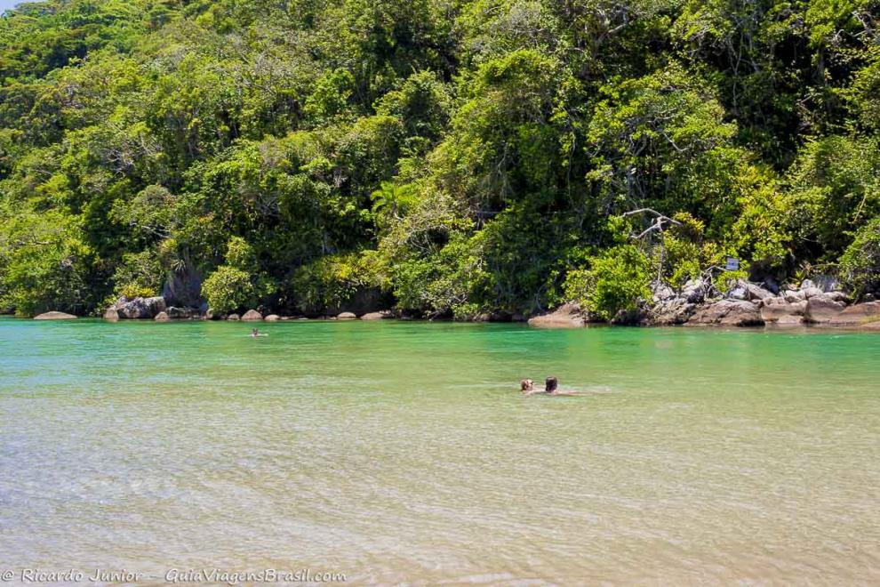 Imagem de duas pessoas nas águas transparentes da Praia do Puruba.